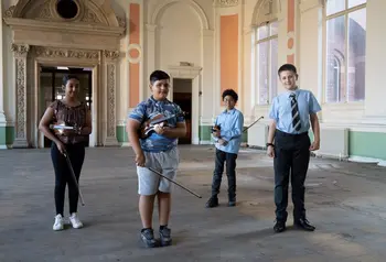 Four young musicians stand together in a large room within Canada House, prior to the restoration.