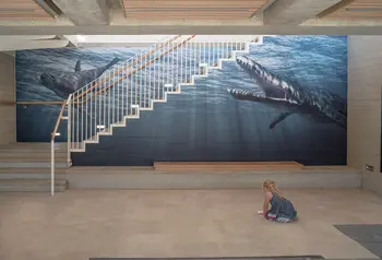 A little girl in front of the image of Jurassic marine life