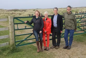 Four people stand in front of a fence
