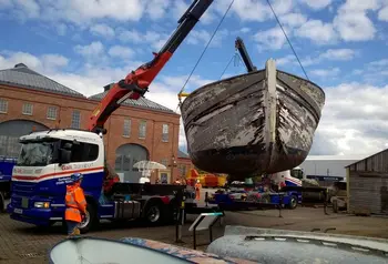 A crane moves a wooden boat