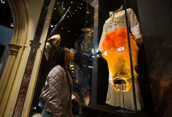 A girl looking at some clothing at The Play’s The Thing exhibition