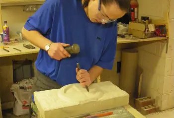 Young person putting their newly gained stone carving skills into practice