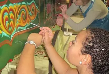 A person painting a colourful design on a wagon