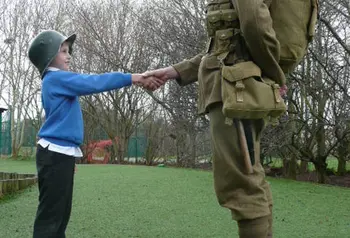 A young participant shaking hands with an actor in period uniform