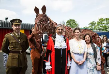 People standing in front of a puppet war horse