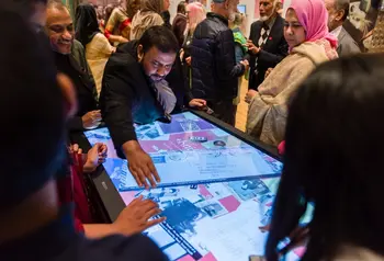 A group of people looking at historic photos on a touch table