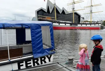 A boy and a girl, stand facing each other on a waterfront near Glasgows Riverside Museum