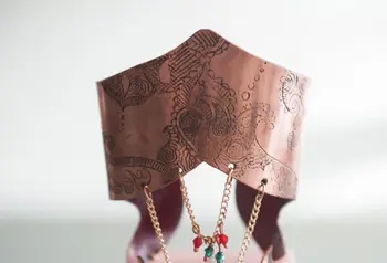 Handmade gold jewellery with red and green gemstones displayed on an intricately carved stand