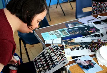 A person at a table looking at photographs and other archive material