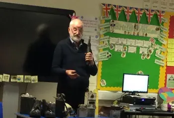An older man with mining objects talking to a group of school children