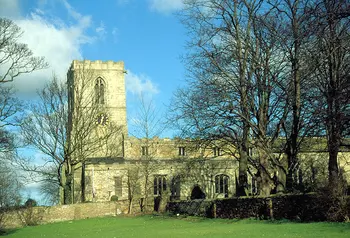 A medieval stone church with trees in front.