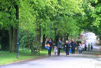 Adults and children walk in Tollcross Park