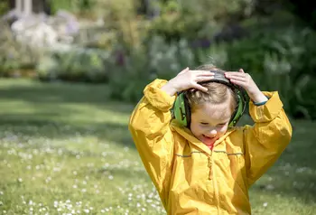 Image of child with headphones on head wearing yellow waterproofs
