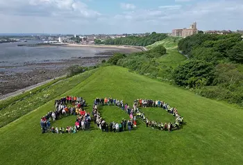 People gather to form the shape of the number 800 on a hill overlooking the mouth of the River Tyne, with the town of North Shields in the background.
