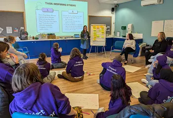 A group of student volunteers listening to a presentation