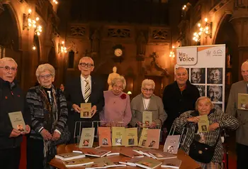 Holocaust survivors and refugees stand with their life story books in Sir John Rylands Library.