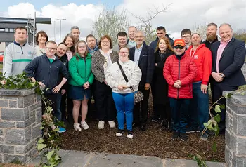 A group of people pose in the entrance of a new walled garden