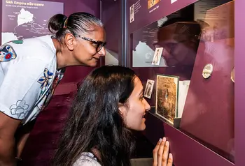 Two people bending down to look at a museum display about Duleep Singh