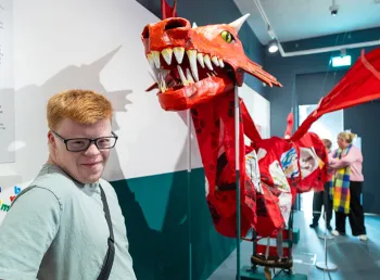 A person stands next to a large hand-made dragon sculpture
