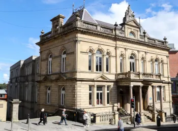 Exterior image of St Columb's Hall, a stone building next to a busy city centre street