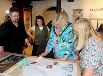 the deputy mayor and a group of people in a museum looking at building plans