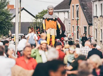 A crowd of people at a procession featuring a giant puppet of Lord Rhys, in Maenclochog.