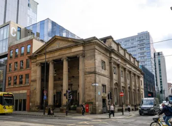 The outside of the 19th-century building with a large stone portico supported by columns