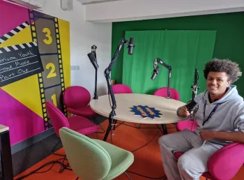 A young person sits at a round table in a recording studio
