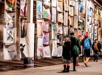Artwork created by local people on display with a group of people studying them. 