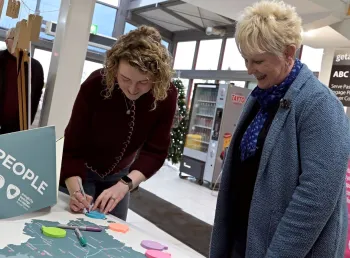 A member of the council team speaks to a member of the community, looking over and annotating a map of the area together.