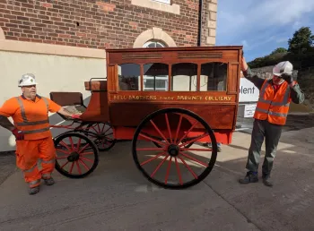 Two workmen standing either side of the horse-drawn ambulance