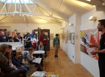 A comic Creator giving a talk in front of a crowd at The Cartoon Museum
