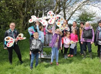 Group of volunteers and children in a park waving paper butterflies