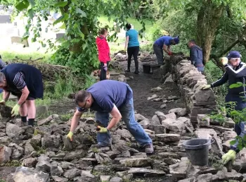 Volunteers work on rebuilding dry stone walls at St Nicholas Church, 
