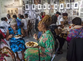 Groups of older people sitting eating at tables at the Migration Museum