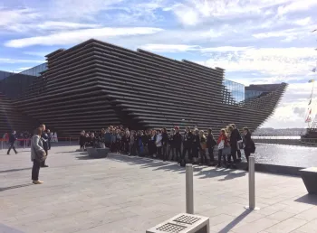A group of people standing outside the V&A Dundee building