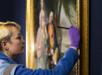 A close up of a person conserving a painting on display in the National Portrait Gallery