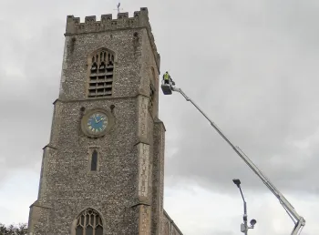 The tower of St Nicholas with a person on a crane assessing the tower roof