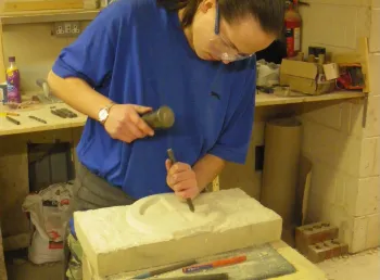 Young person putting their newly gained stone carving skills into practice