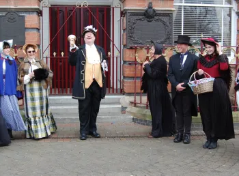 A bell ringer and other people in historic dress