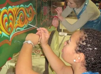 A person painting a colourful design on a wagon