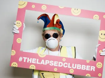 A lapsed clubber holding a picture frame, dressed in typical clubbing paraphernalia from the late 80s