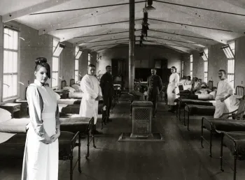 Participant as a VAD (Voluntary Aid Detachment) nurse in front of a green screen with an image of a First World War hospital
