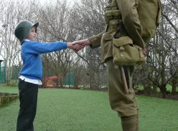 A young participant shaking hands with an actor in period uniform