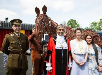 People standing in front of a puppet war horse