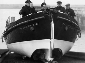 Five men stand in a life boat ready to be launched