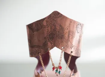Handmade gold jewellery with red and green gemstones displayed on an intricately carved stand