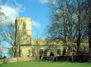 A medieval stone church with trees in front.