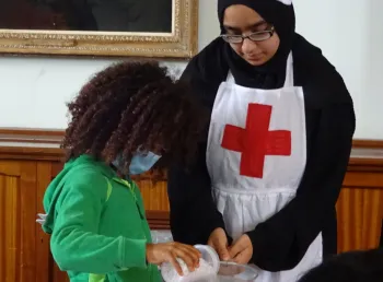 A young participant demonstrates wartime medical techniques to a young visitor