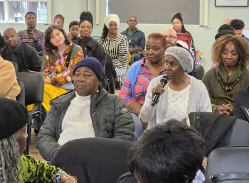A seated audience turning to listen to an audience member holding a microphone